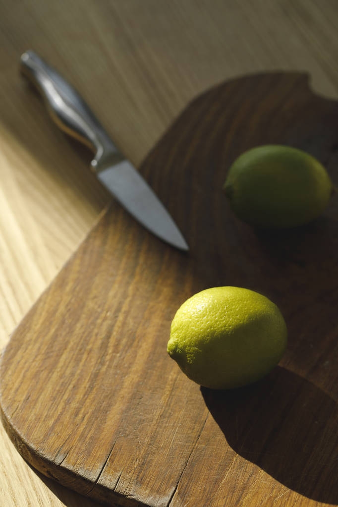 vista aérea de limas e faca na placa de madeira na mesa
 - Foto, Imagem