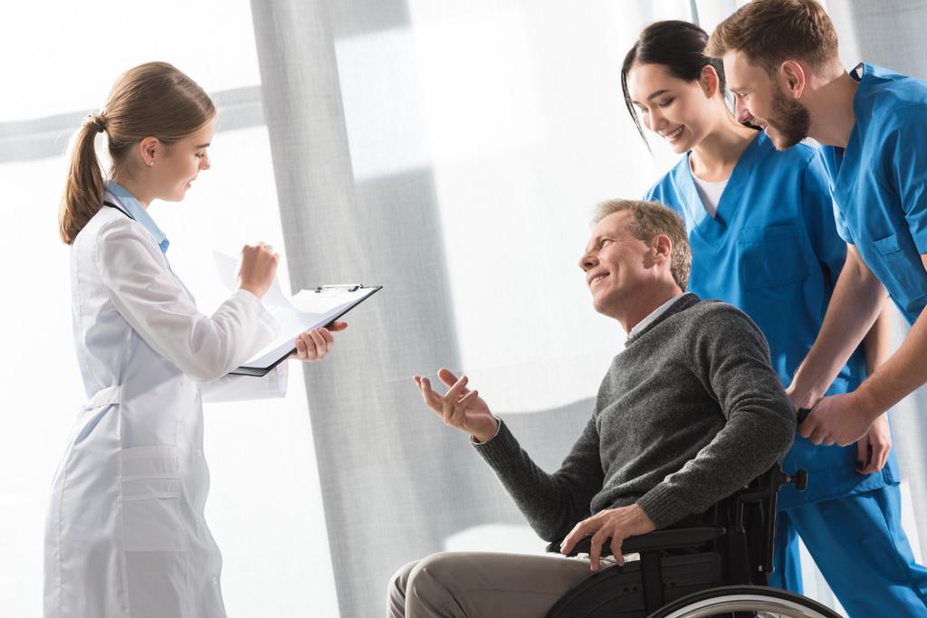 Medico che parla con paziente di mezza età sulla sedia a rotelle
  - Foto, immagini