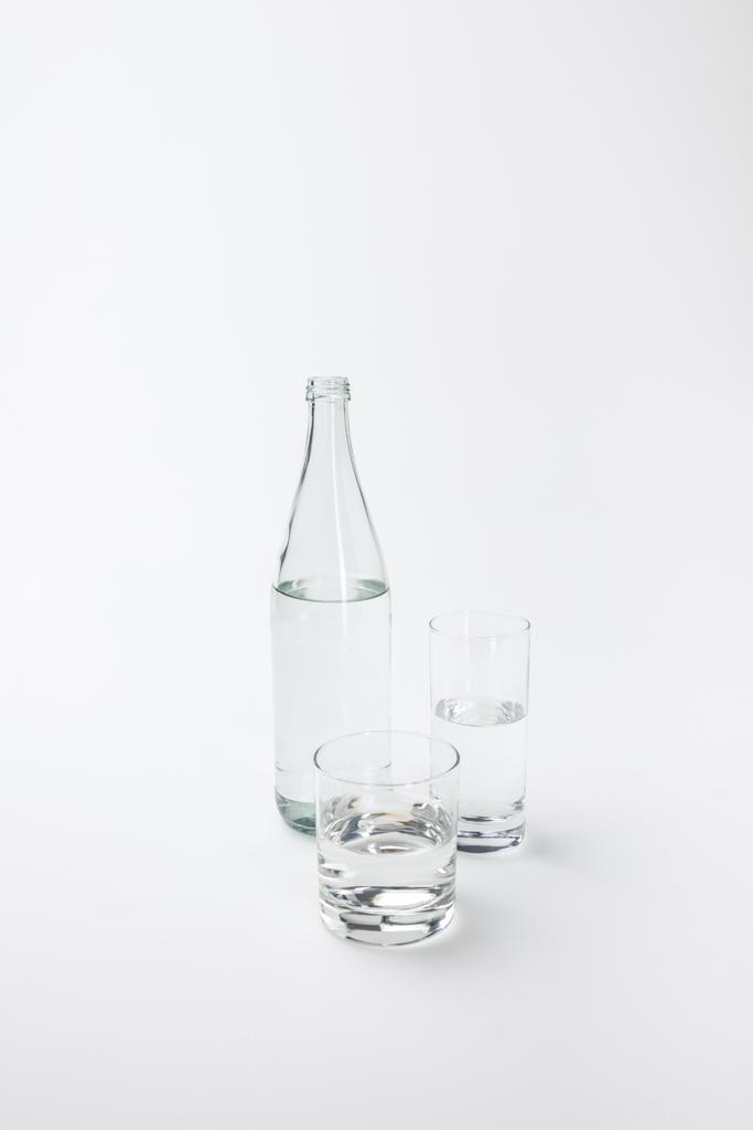 δύο διαφορετικά γυαλιά και ένα μπουκάλι με ήρεμα νερά που απομονώνονται σε λευκό  - Φωτογραφία, εικόνα