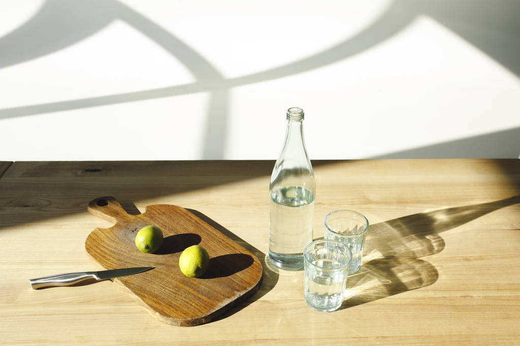 ミネラルウォーターと木製のテーブルでレモネードを準備するためのライム   - 写真・画像