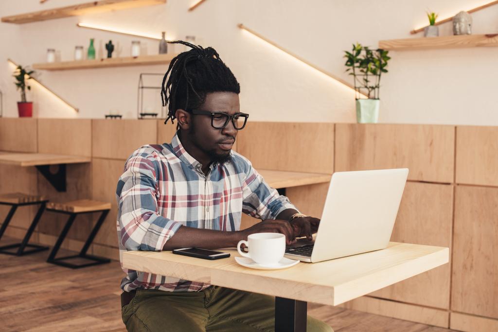Afryki amerykański człowieka za pomocą laptopa i smartfon w kawiarni - Zdjęcie, obraz