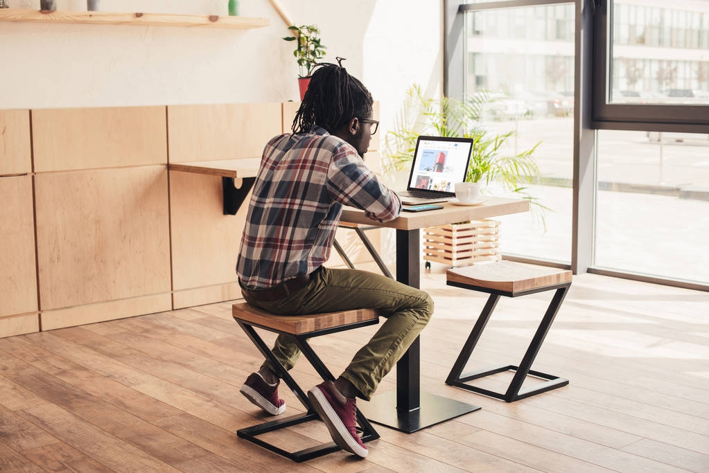 назад вид африканский американец с помощью ноутбука с Ebay веб-сайт в кафе
 - Фото, изображение