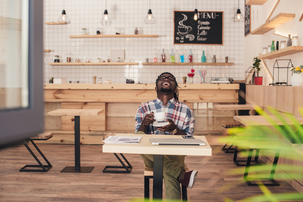 riant homme afro-américain boire du café à table dans un café
 - Photo, image