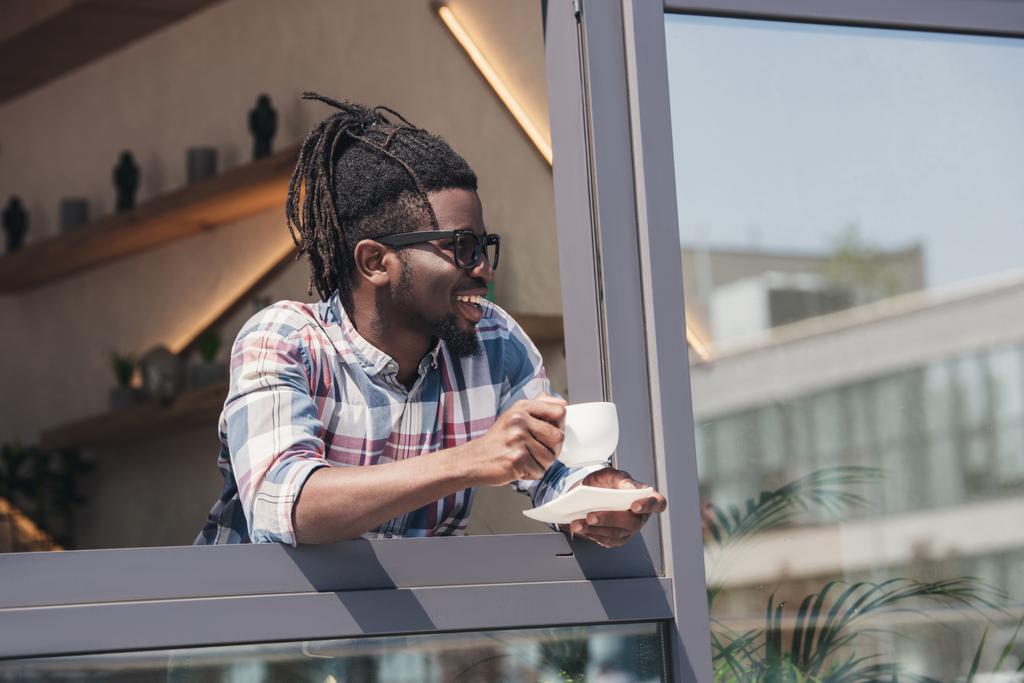 カフェでコーヒーを飲みながら陽気なアフリカ系アメリカ人 - 写真・画像