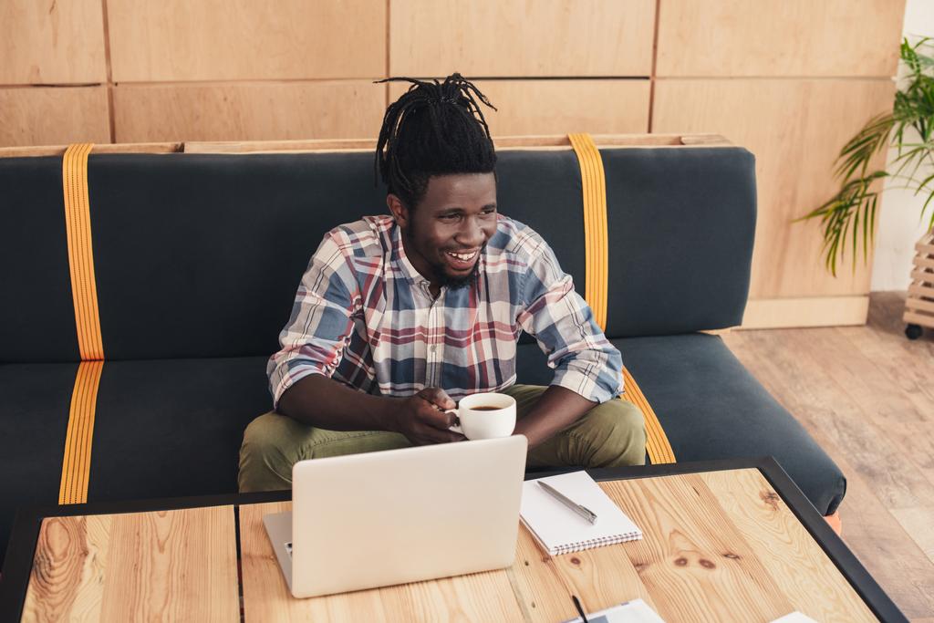 Африканский американец с ноутбуком пьет кофе в кафе
 - Фото, изображение