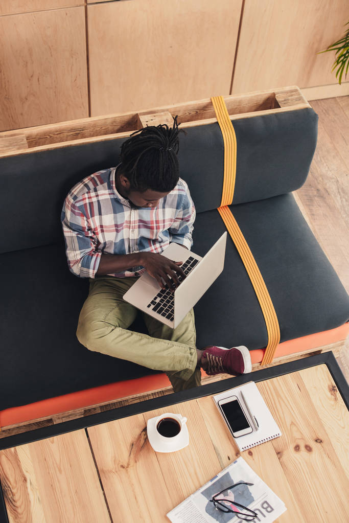 вид сверху на африканского американца с помощью ноутбука в кофейне
 - Фото, изображение