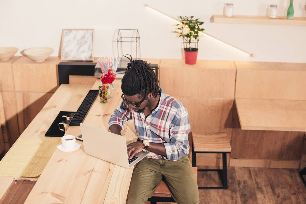 Αφρικανική αμερικανική άνθρωπος που χρησιμοποιούν φορητό υπολογιστή στο μπαρ μετρητή σε καφενείο - Φωτογραφία, εικόνα