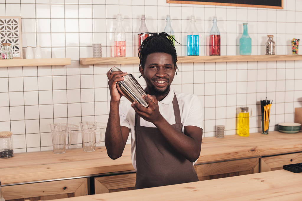 Afro-Amerikaanse barman in shaker op toog cocktail maken - Foto, afbeelding