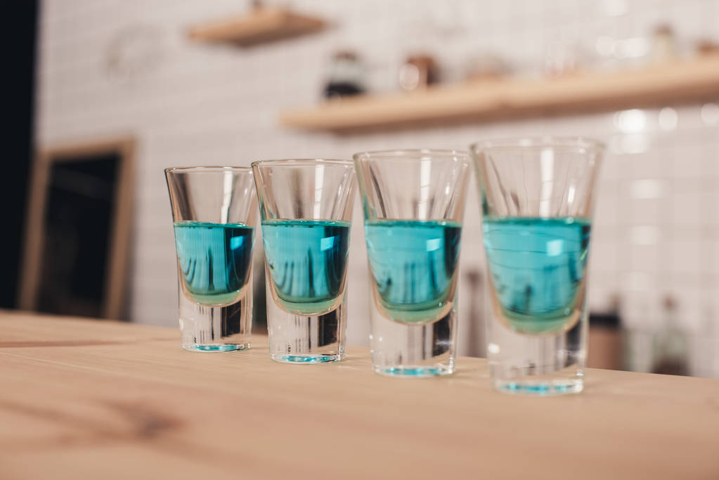 primer plano de cócteles azules en vasos de chupito de pie en el mostrador del bar
 - Foto, Imagen