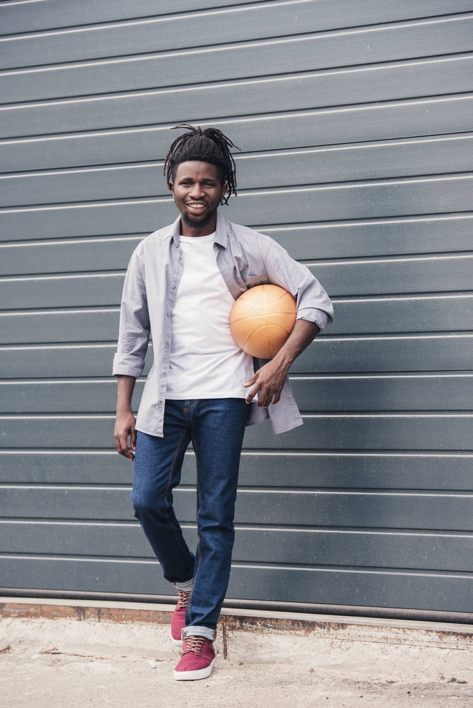 bonito sorrindo afro-americano homem com bola de basquete na rua
 - Foto, Imagem