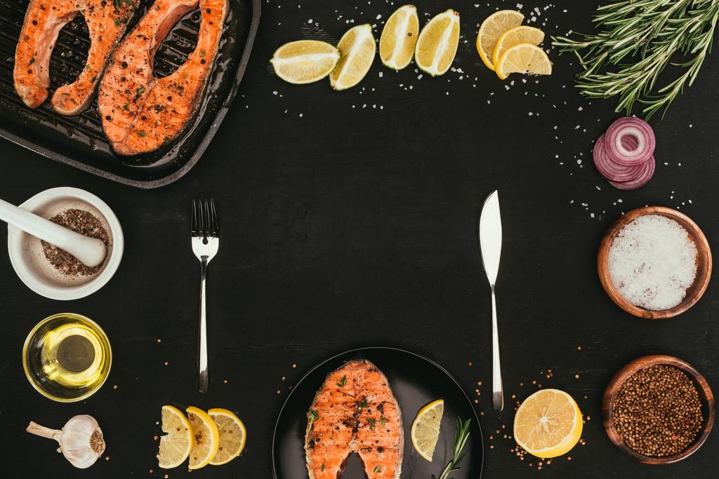 vue de dessus des steaks de saumon grillés, des couverts et des épices sur noir
 - Photo, image