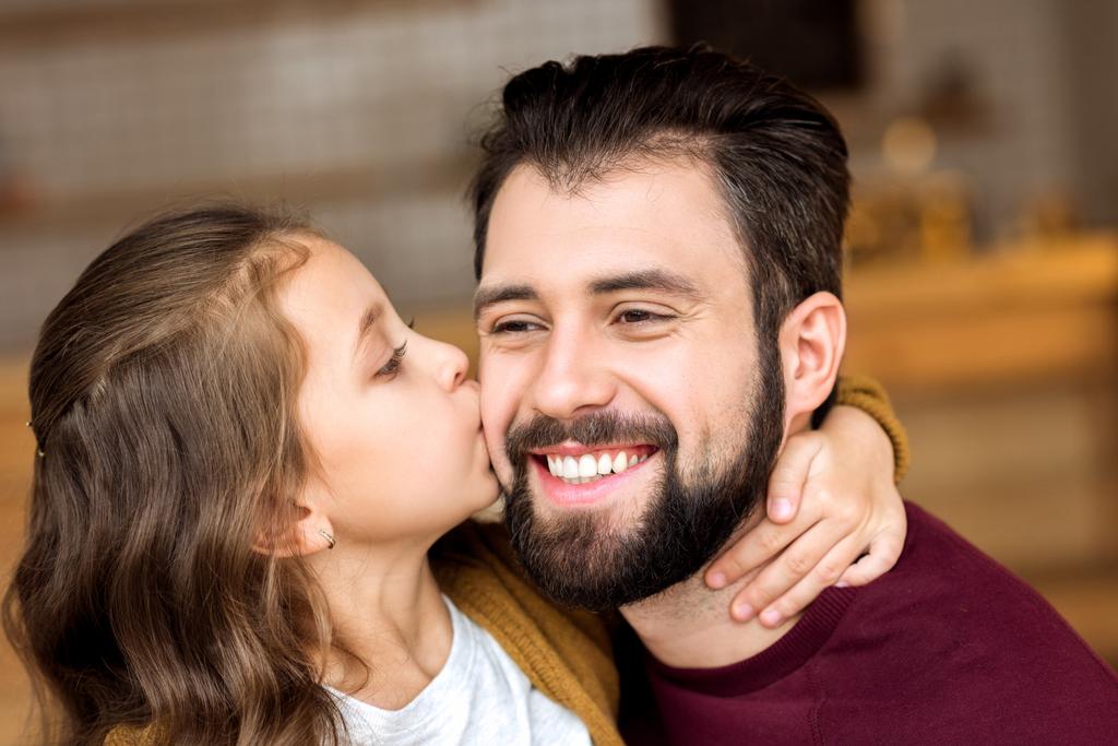 Portret van dochter kussen lachende vader in café - Foto, afbeelding
