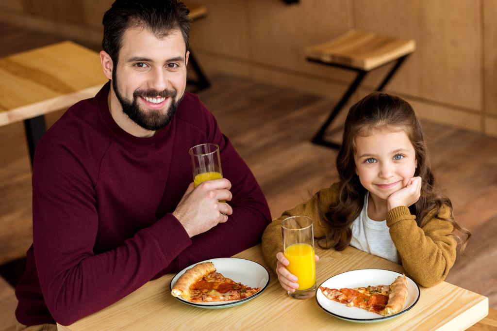 feliz padre e hija bebiendo jugo de naranja en la cafetería y mirando a la cámara
 - Foto, Imagen