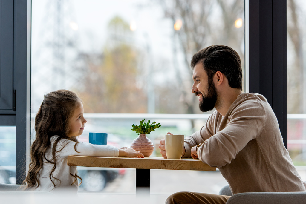 щасливий батько і дочка сидять в кафе і дивляться один на одного
  - Фото, зображення