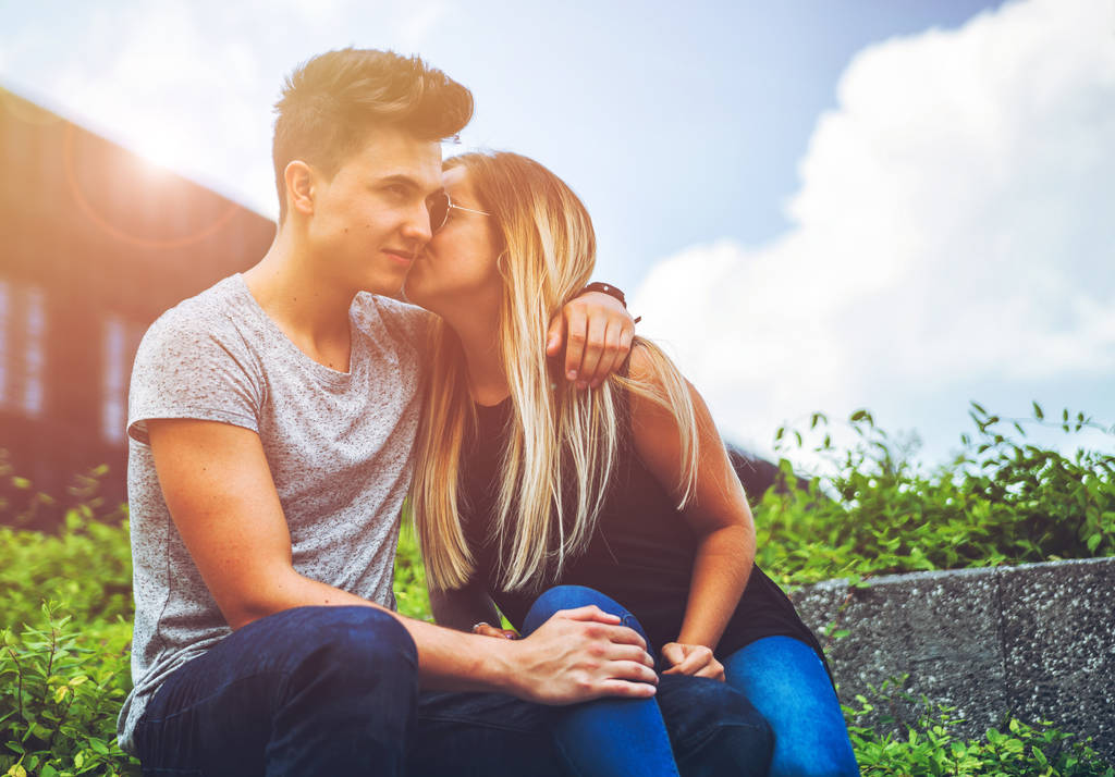 Mladý pár sedící venkovní a dává pusu, štěstí koncepce - Fotografie, Obrázek