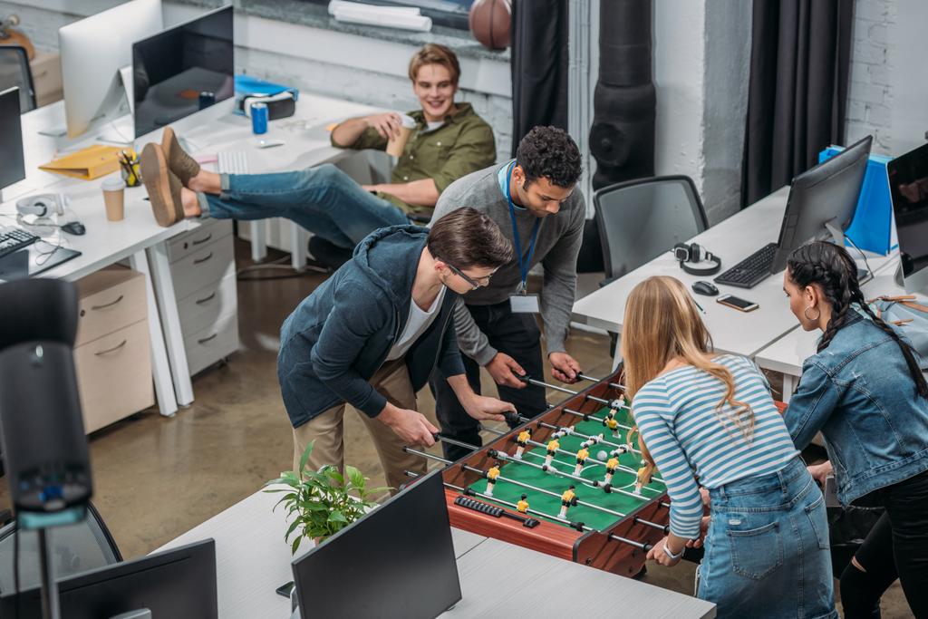 近代的なオフィス テーブル サッカーで遊んで多民族の同僚 - 写真・画像
