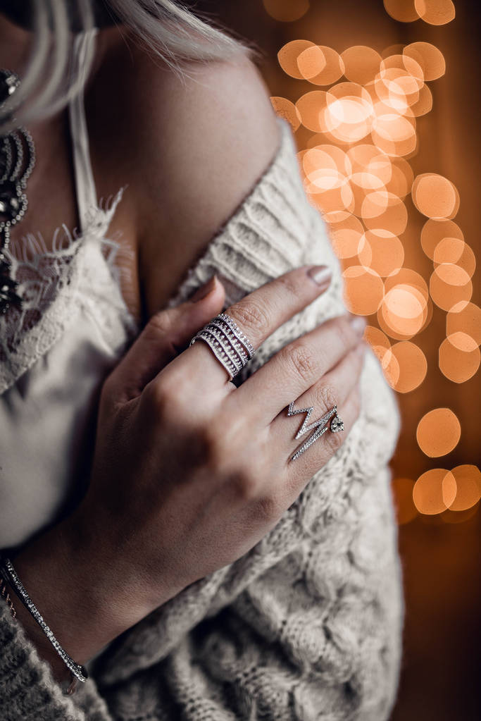 Ręka z srebrne pierścionki na złote bokeh świeci tło - Zdjęcie, obraz