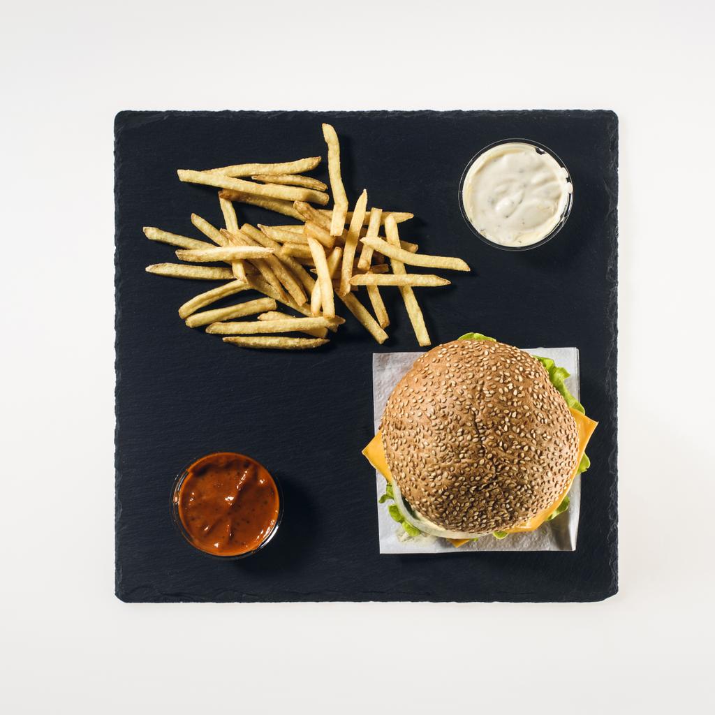 vista dall'alto di hamburger, patatine fritte e salse su tavola di pietra nera, isolato su bianco
 - Foto, immagini