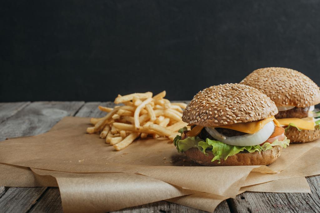 cheeseburger tradizionali fatti in casa su carta da forno con patatine fritte
 - Foto, immagini