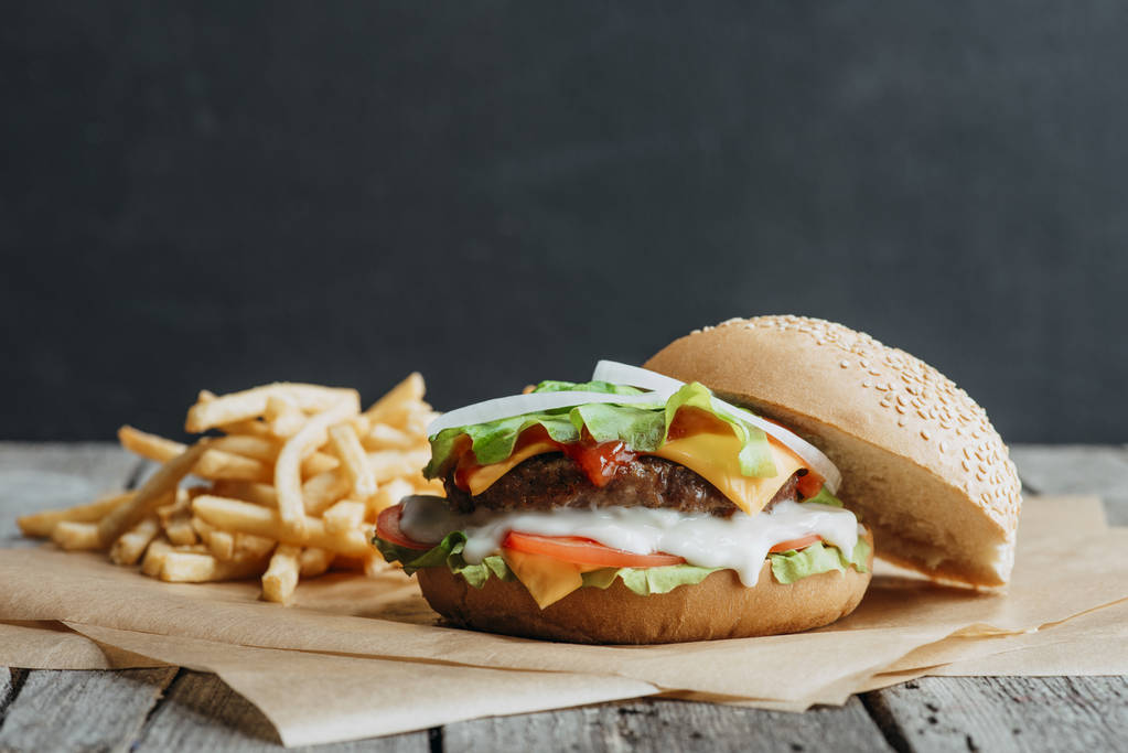 traditionelle hausgemachte Burger auf Backpapier mit Pommes frites - Foto, Bild
