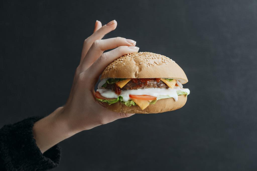 przycięte widzenia ręka z domu cheeseburger dla smakoszy na czarny - Zdjęcie, obraz