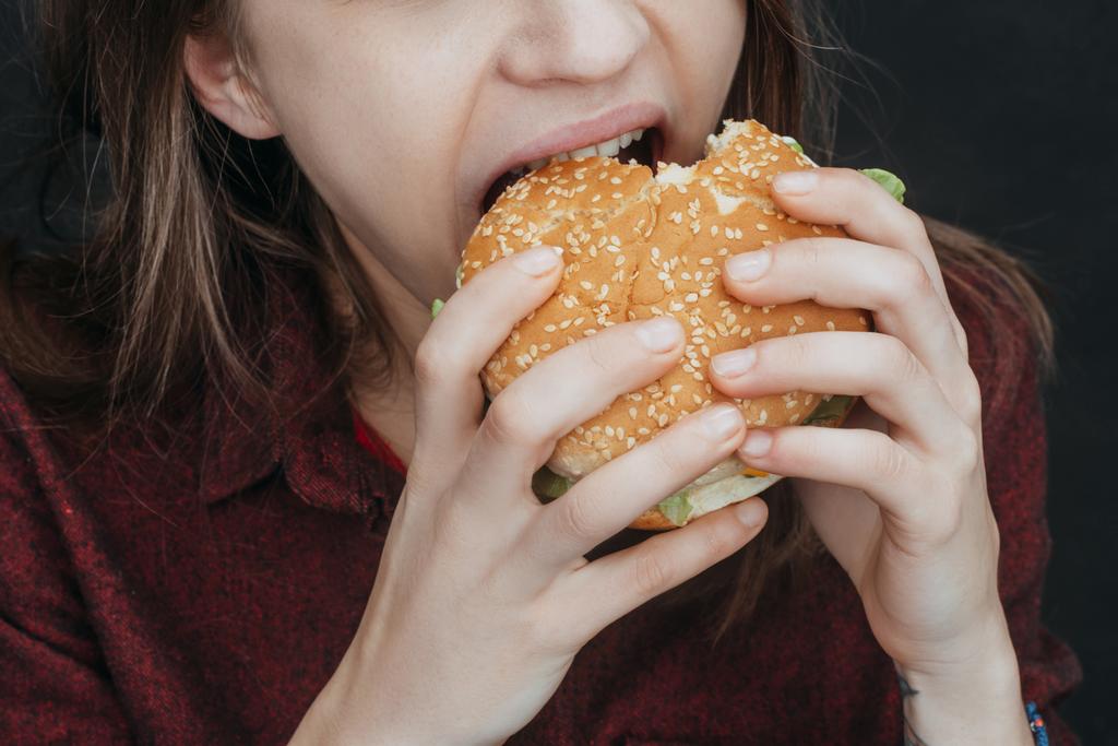 lezzetli hamburger ısırma kız görünümünü kırpılmış  - Fotoğraf, Görsel