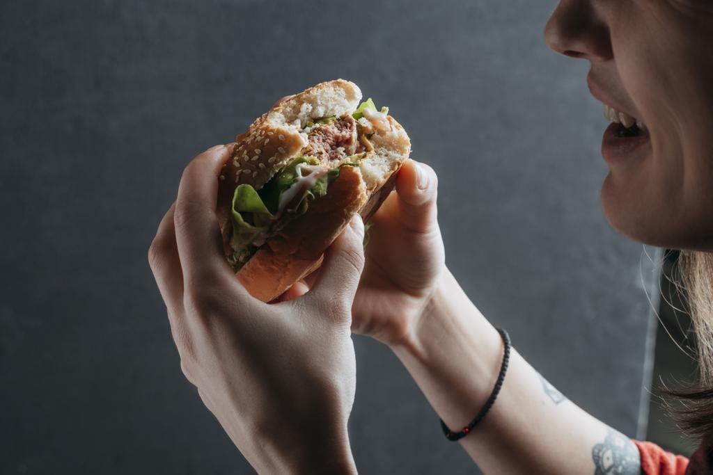 przycięte widzenia kobieta jedzenie smaczne hamburger - Zdjęcie, obraz