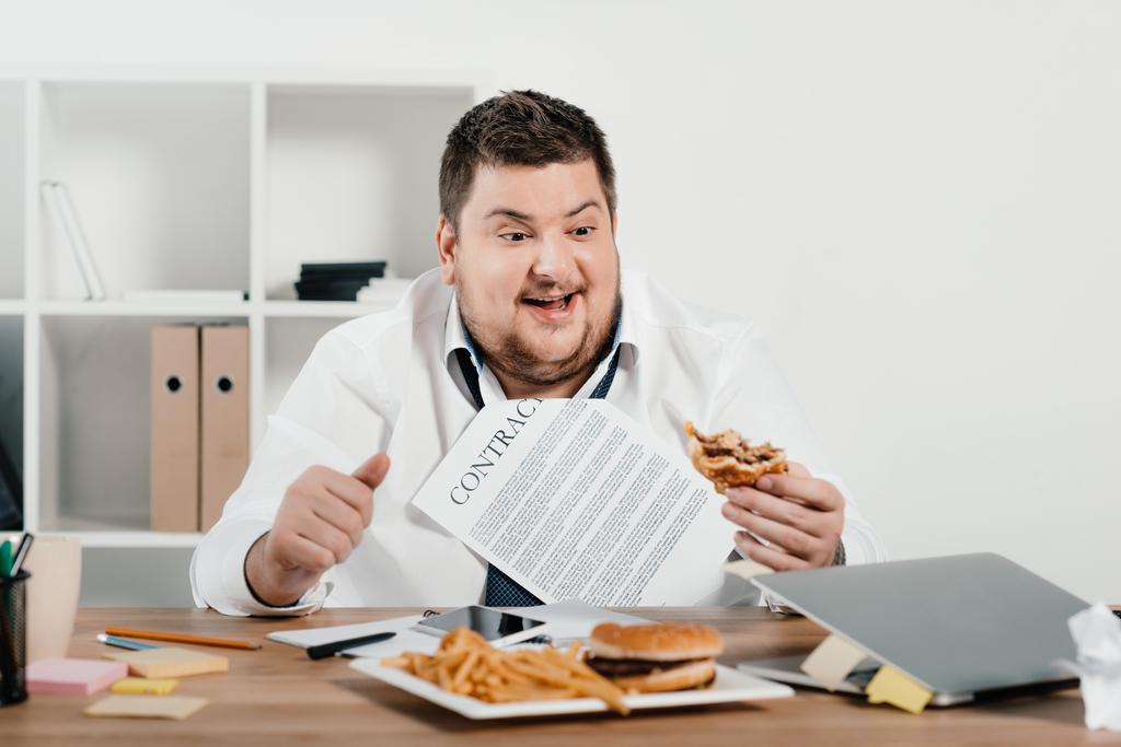 λίπος επιχειρηματίας τρώει χάμπουργκερ και πατάτες τηγανητές στο γραφείο - Φωτογραφία, εικόνα