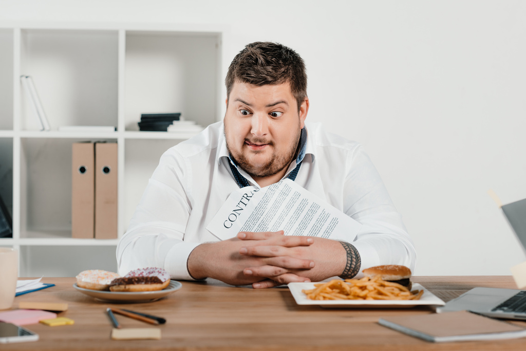 hungrige übergewichtige Geschäftsleute wählen Donuts oder Hamburger mit Pommes zum Mittagessen - Foto, Bild