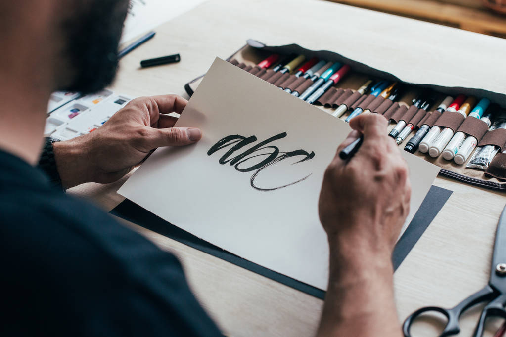 hombre aprendizaje caligrafía letras escritura a mano sobre papel de dibujo en la mesa con estuche de lápiz
 - Foto, imagen
