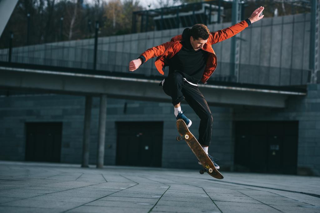Skateboarder doing jump trick in urban location
 - Фото, изображение