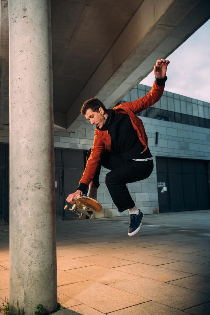 стильный молодой скейтбордист, выполняющий трюк прыжка в городской местности
 - Фото, изображение