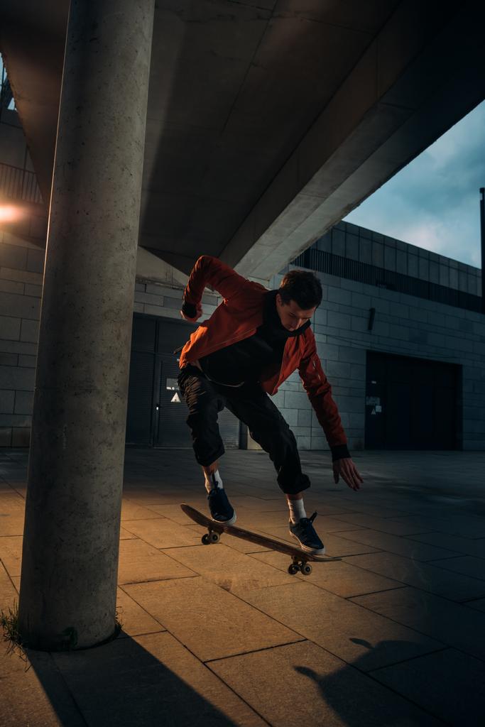 Skateboarder vollführt am Abend Sprungtrick in urbaner Lage - Foto, Bild