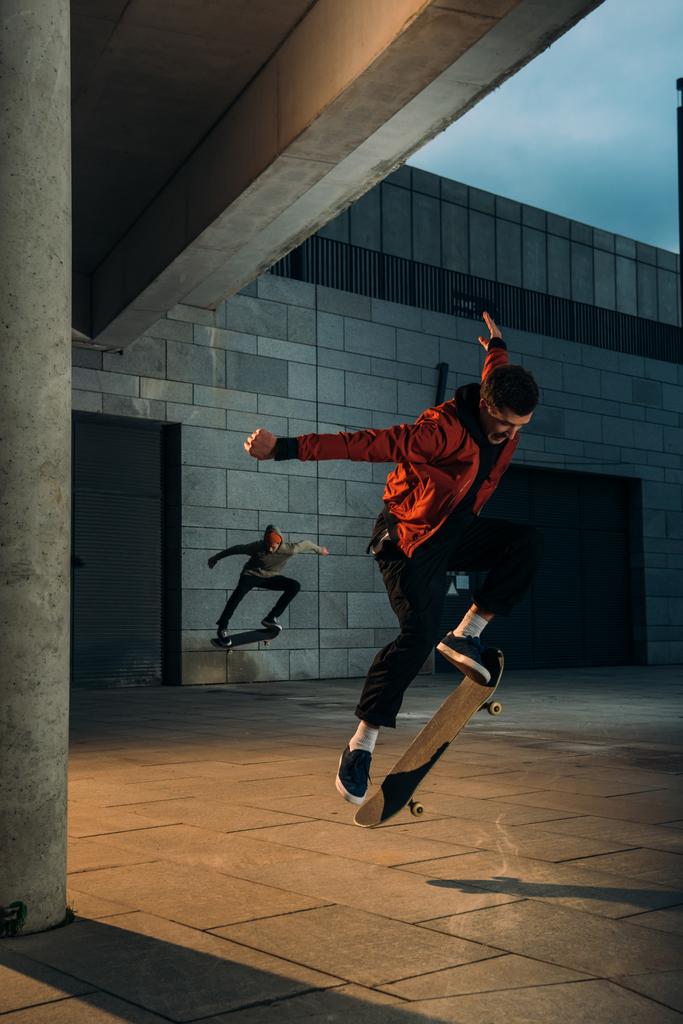 skateboarders performing jump tricks together at urban location - Photo, Image