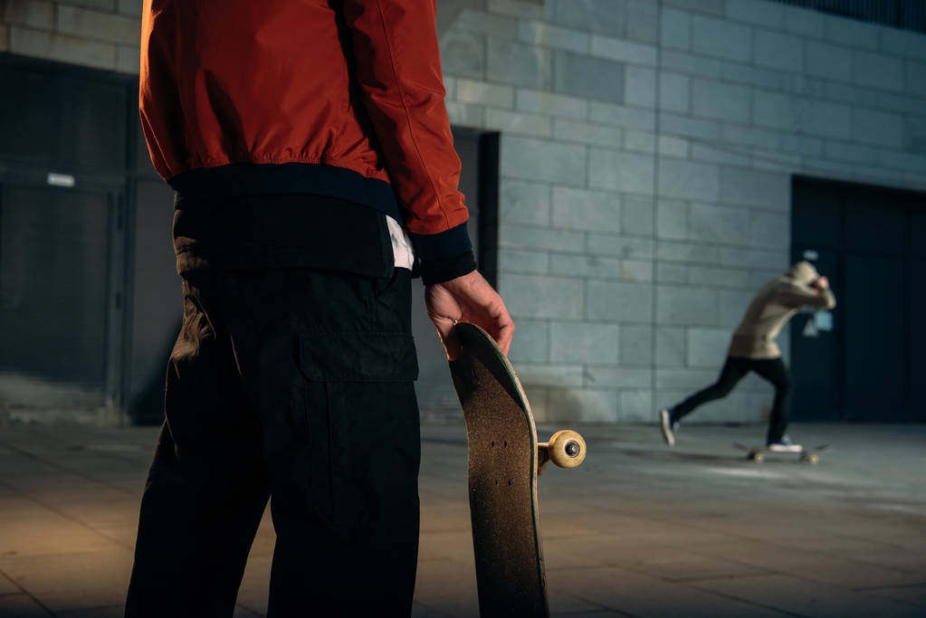 ritagliato colpo di uomo in piedi con skateboard e guardando il suo compagno di equitazione
 - Foto, immagini