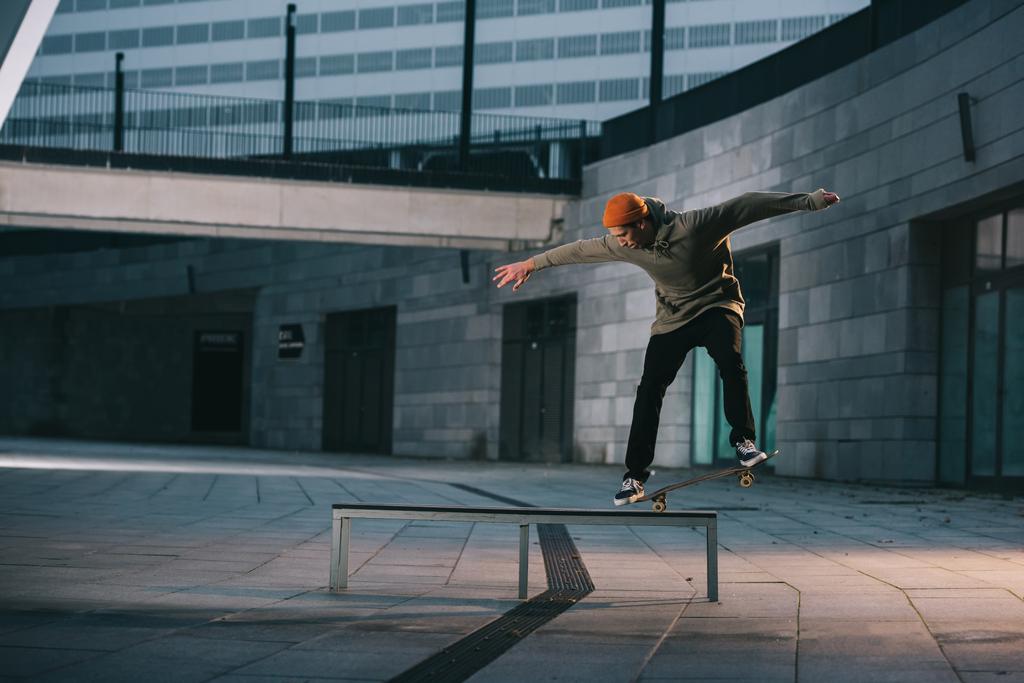 скейтбордист балансирует с доской на скамейке в городской местности
 - Фото, изображение