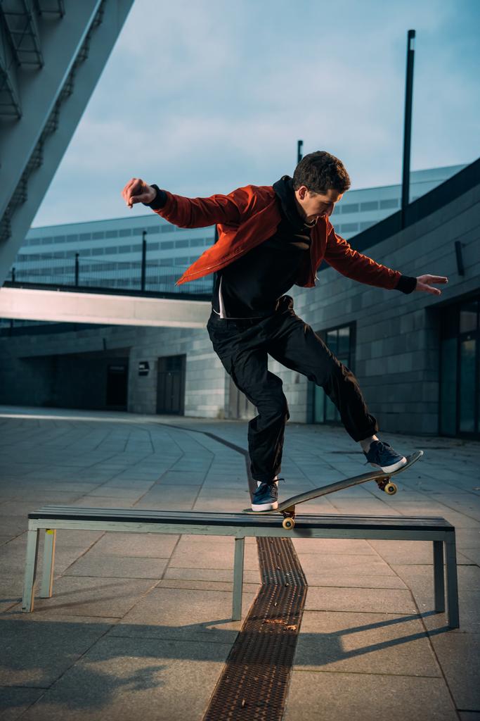 молодой скейтбордист, выполняющий трюк на скамейке
 - Фото, изображение