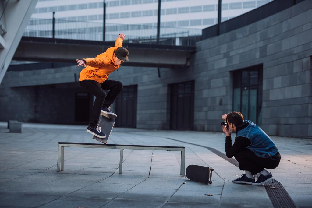 man taking photo of skateboarder doing trick over bench - Photo, Image