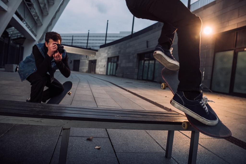 крупным планом человек фотографирует скейтбордиста, делающего трюк
 - Фото, изображение