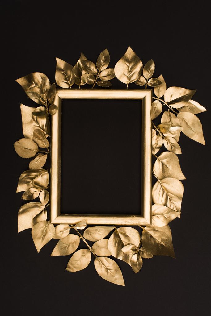 top view of golden photo frame and leaves isolated on black - Photo, Image