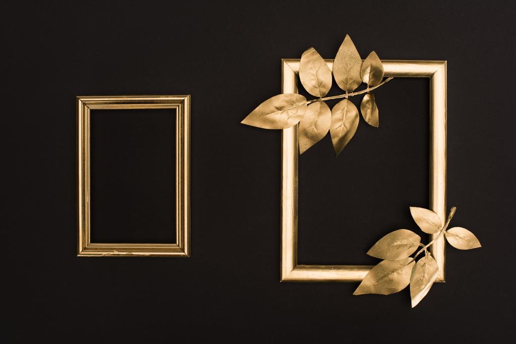 top view of golden photo frames and leaves isolated on black - Photo, Image
