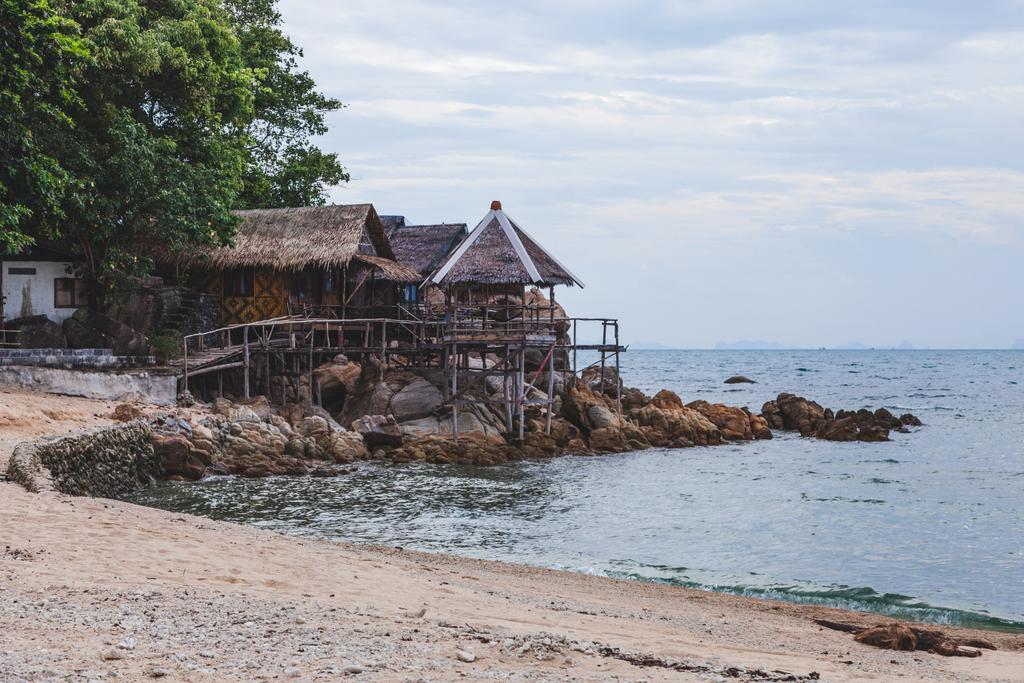 уютные деревянные хижины на берегу моря в пасмурный день
 - Фото, изображение