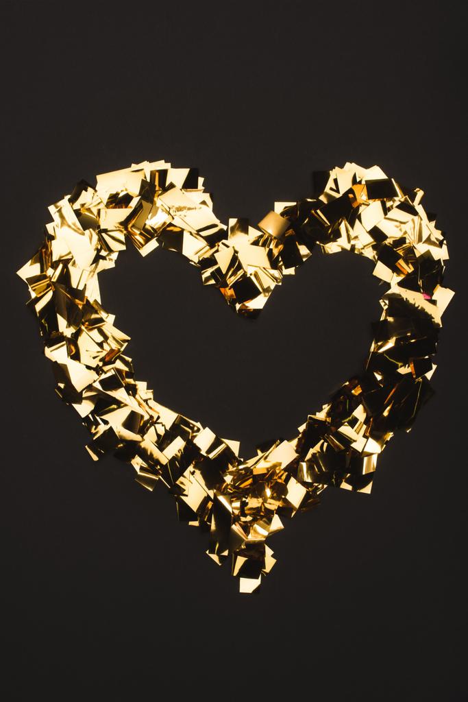 вид зверху на золоту конфетті, розташовану у формі серця ізольовано на чорному
 - Фото, зображення