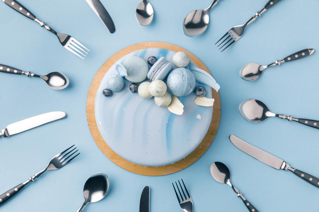 top view of blue cake surrounded by flatware isolated on blue - Photo, Image