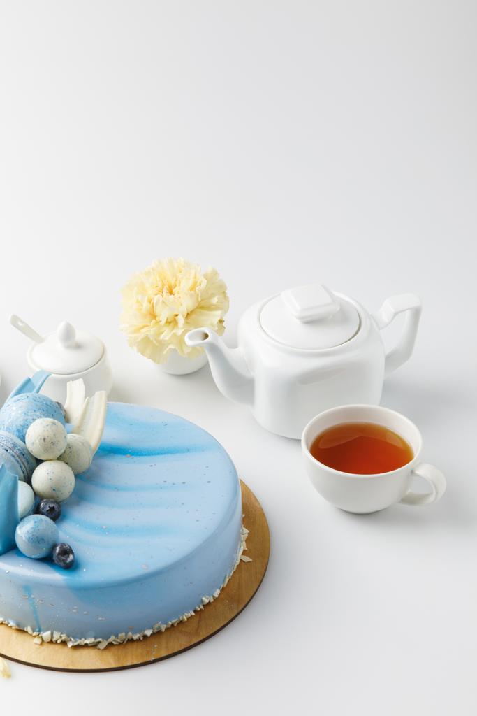gâteau savoureux bleu sur planche à découper avec thé et fleur isolé sur blanc
 - Photo, image