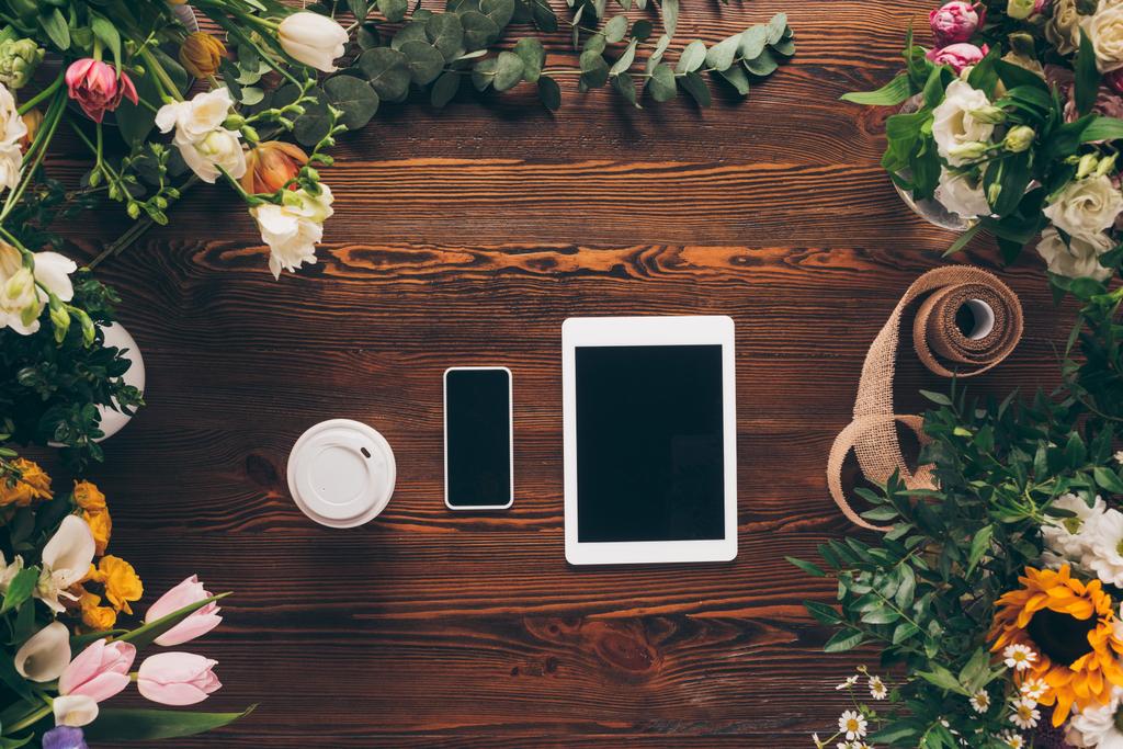 花とテーブルの紙コップ、スマート フォンやタブレットでのコーヒーのトップ ビュー - 写真・画像