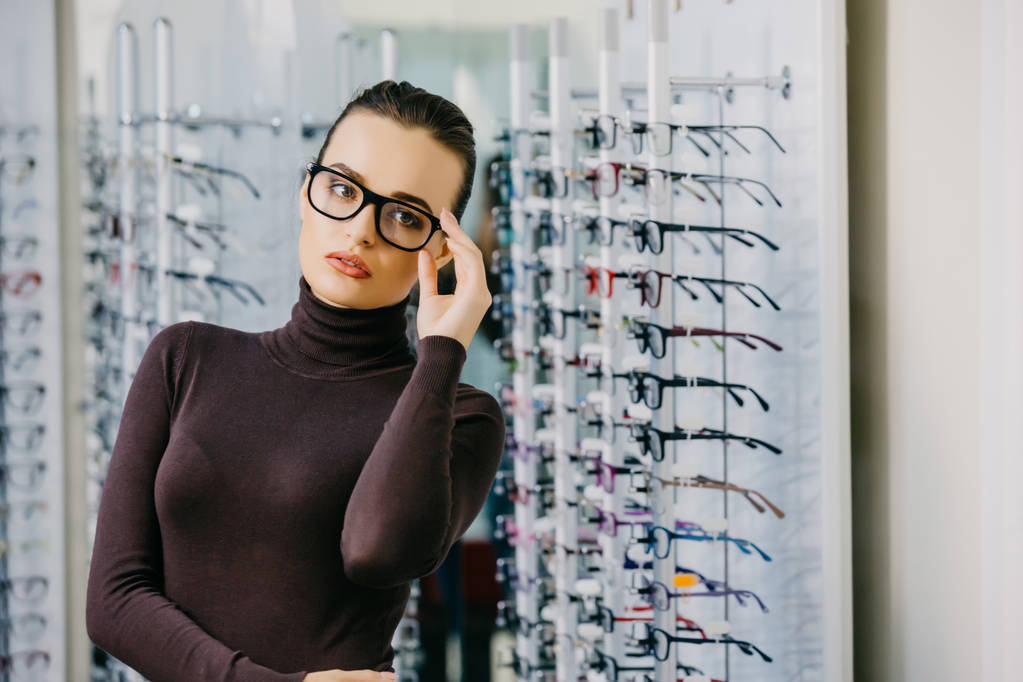 Beautiful girl wearing glasses in optician shop. Eyesight correction. Optics. Emotions. Ophthalmology. - Photo, Image