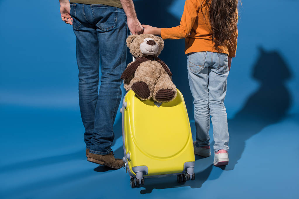 immagine ritagliata di padre e figlia che vanno con borsa da viaggio su blu
 - Foto, immagini