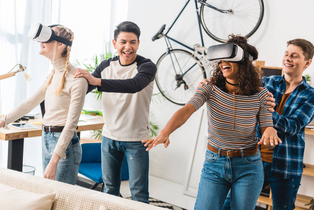 riant garçons tenant filles multiculturelles regarder quelque chose avec des casques de réalité virtuelle
  - Photo, image