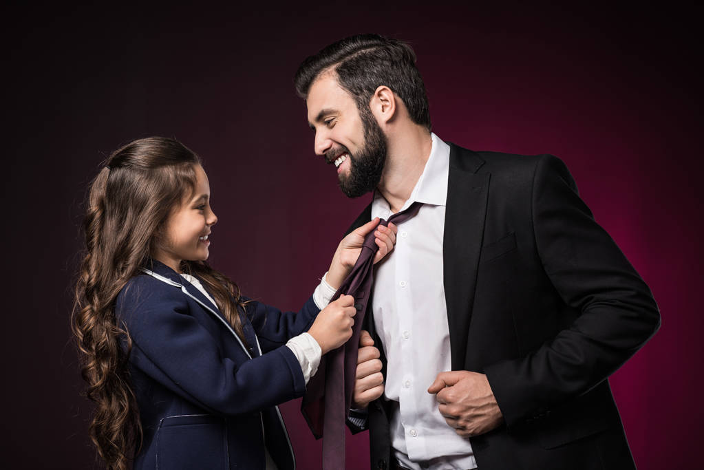 souriant fille fixation père cravate sur bordeaux
 - Photo, image